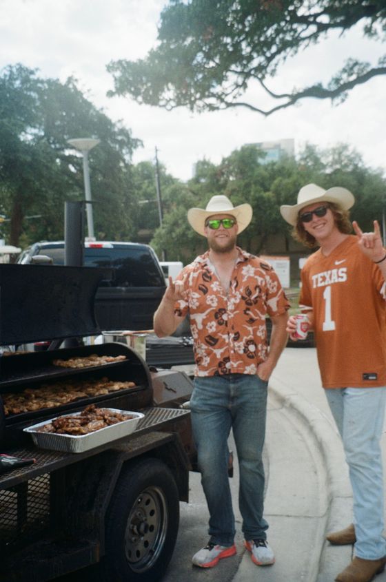 Two of the crew at the smoker with a tray of barbecue.