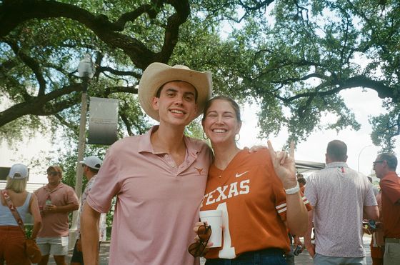 Two tailgate guests under the oaks on a home game day.